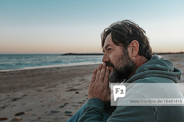 Thoughtful mature man sitting at beach