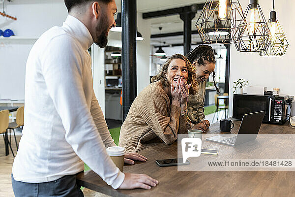 Happy business people with coffee cup sitting at table in office cafeteria