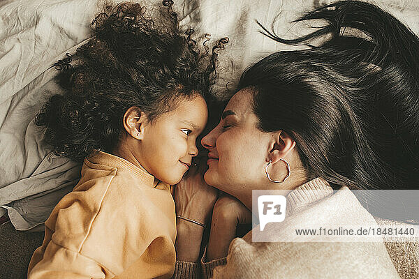 Smiling mother with daughter lying on bed at home