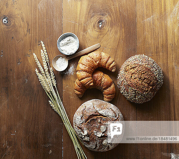 Freshly baked loaves of bread and croissants on wooden table