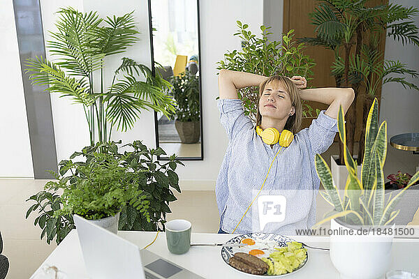 Freelancer with hands behind head relaxing at desk at home