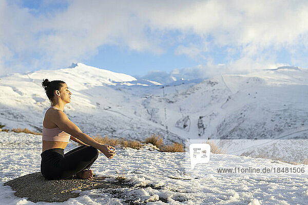 Woman meditating on snowcapped mountain