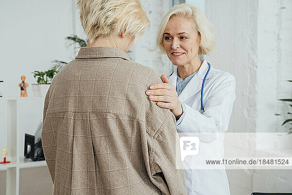 Lächelnder Arzt tröstet Patienten in der Klinik