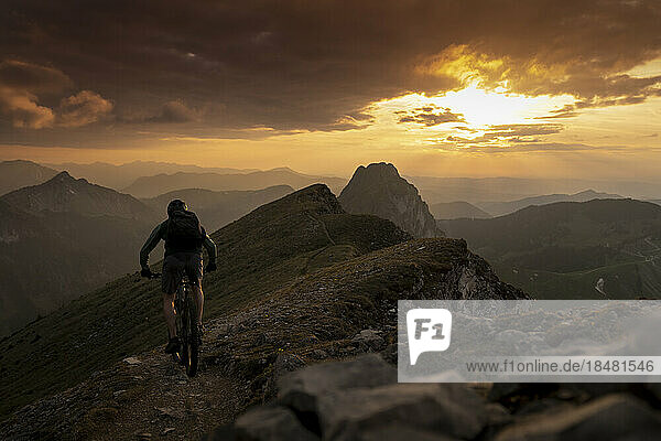 Man cycling on mountain at sunset