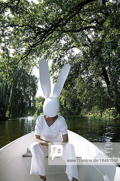Frau mit weißer Kaninchenmaske sitzt im Boot