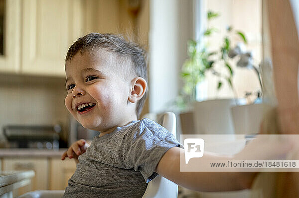 Happy boy sitting in kitchen at home