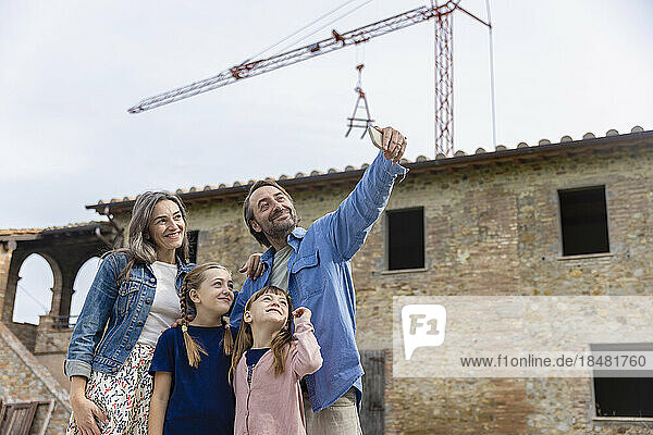 Glücklicher Mann macht Selfie mit der Familie vor dem Haus