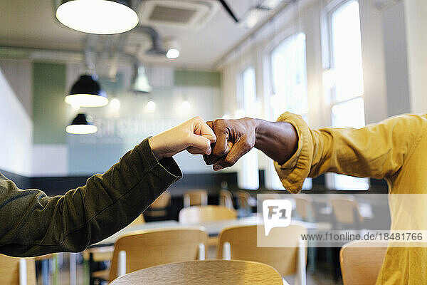 Hands of business colleagues giving fist bump at office