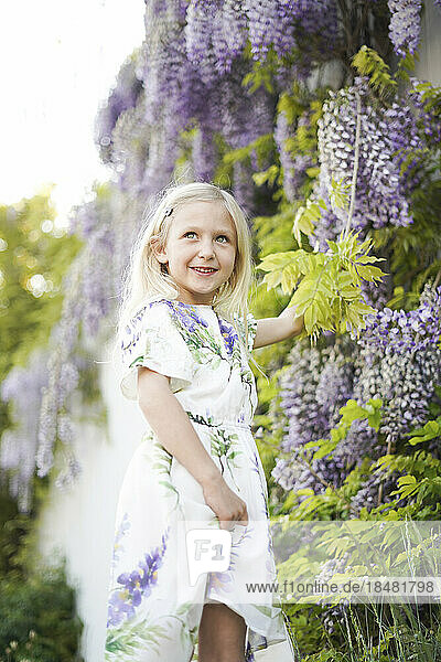Smiling girl standing near Wisteria flowers