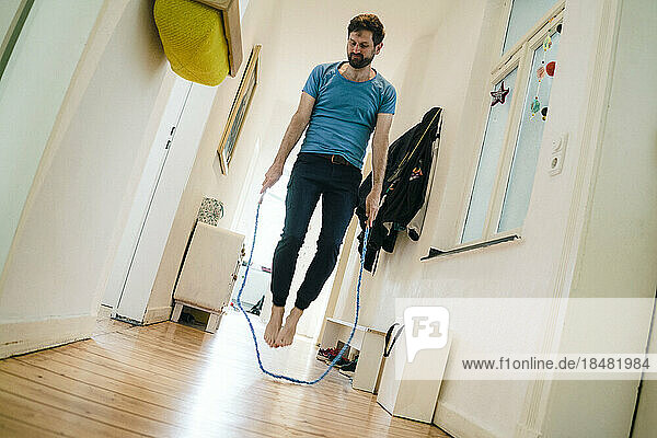 Man doing skipping ropes in corridor at home