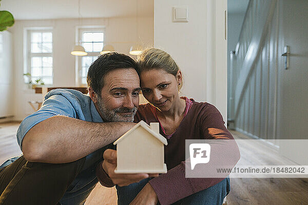 Mann und Frau schauen sich das Hausmodell an  das zu Hause sitzt