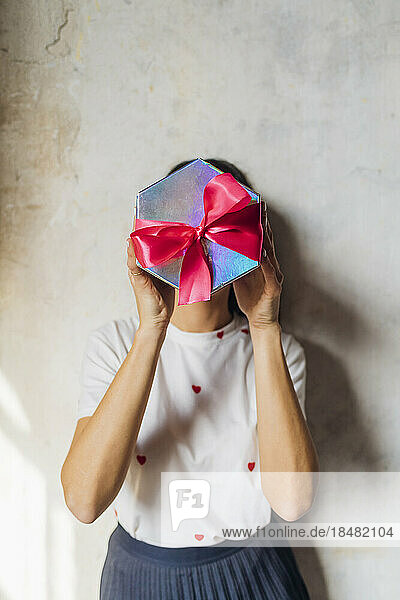 Frau bedeckt Gesicht mit Geschenkbox