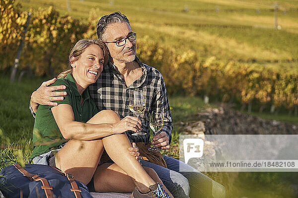 Thoughtful couple sitting with wineglasses on wall