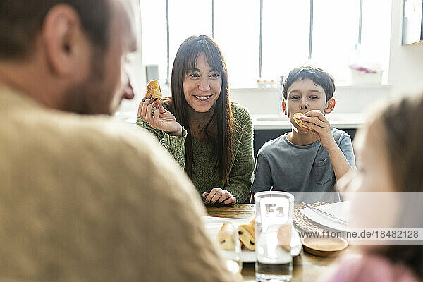 Happy woman with family having breakfast together at home
