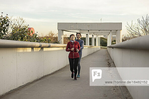 Happy mature man and woman running and enjoying on bridge