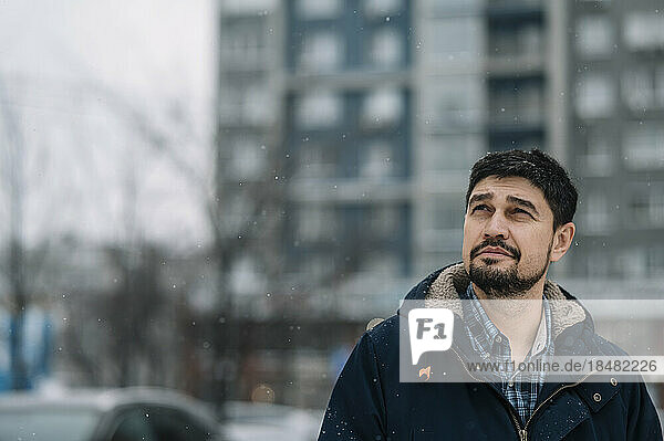 Contemplative man wearing warm clothing in snowy weather
