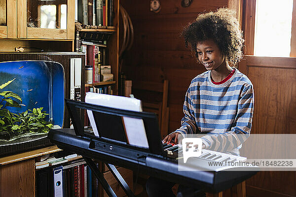 Smiling boy practicing electric piano at home