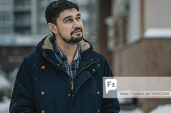 Thoughtful man wearing warm clothing in snowfall
