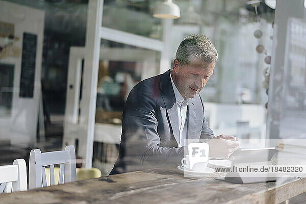 Geschäftsmann frühstückt und nutzt Tablet-PC im Café