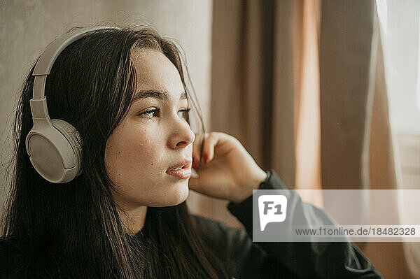 Thoughtful teenage girl wearing bluetooth headphones
