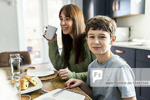 Smiling boy with mother having breakfast at table