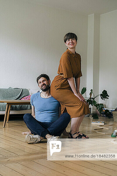 Reifer Mann mit gekreuzten Beinen von Frau im heimischen Wohnzimmer
