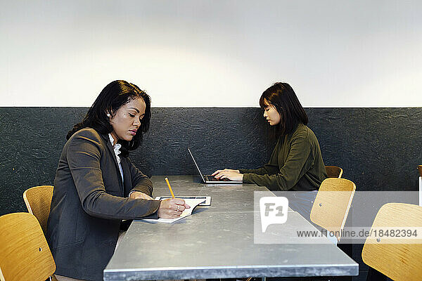 Businesswomen working together sitting at desk in office
