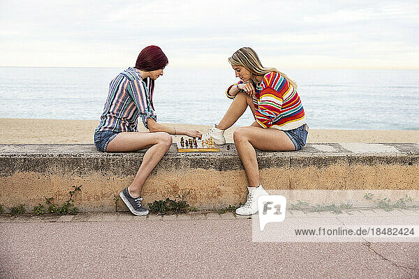 Friends playing chess at promenade in front of sea
