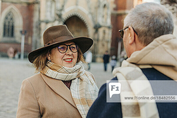 Smiling senior woman wearing hat talking to man
