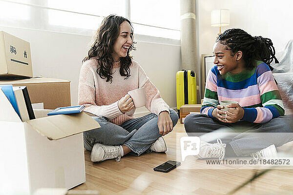Happy multiracial friends having coffee at new home