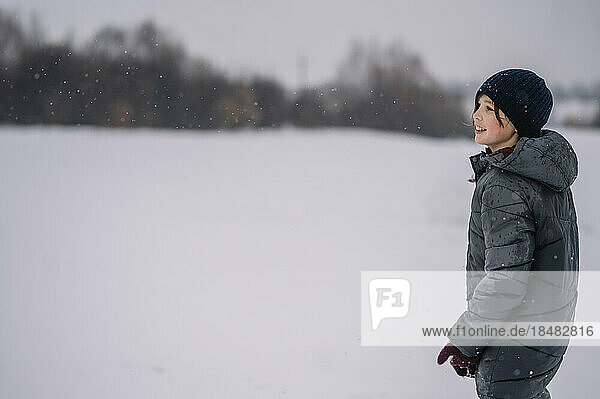 Smiling boy wearing knit hat standing in snow