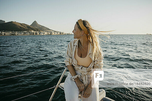 Lächelnde Frau sitzt am Wochenende auf einem Boot im Meer