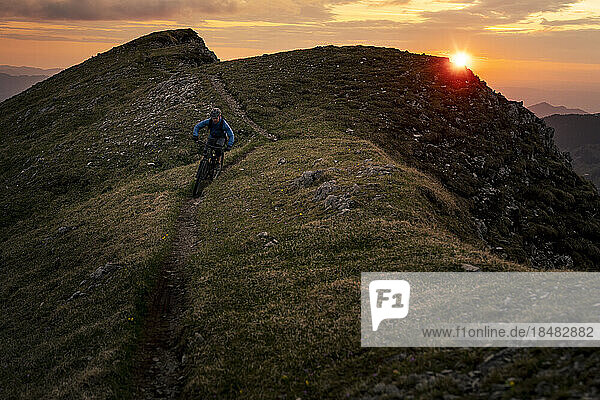 Mann fährt Mountainbike bei Sonnenuntergang