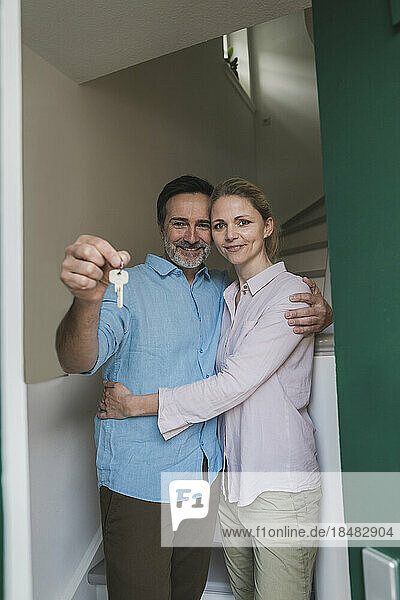 Smiling woman with husband holding house key at home