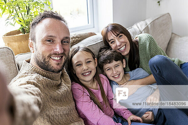 Happy man taking selfie with family at home