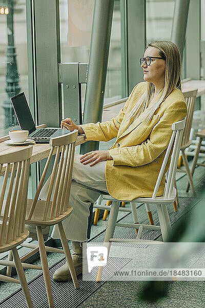 Thoughtful businesswoman sitting on chair at cafe