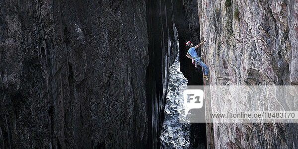 Man climbing rocky wall on mountain