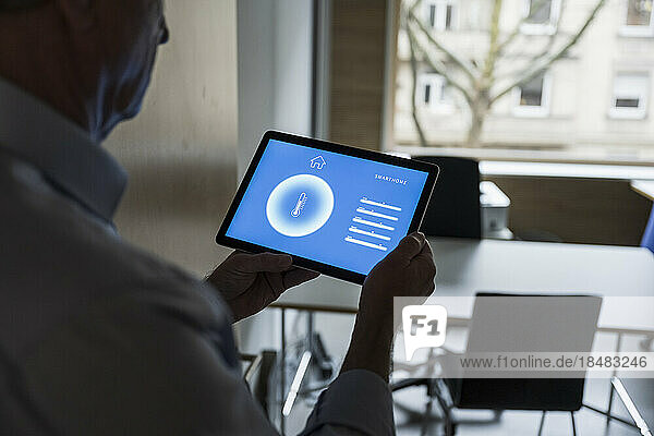 Businessman with tablet PC showing home automation app display at office