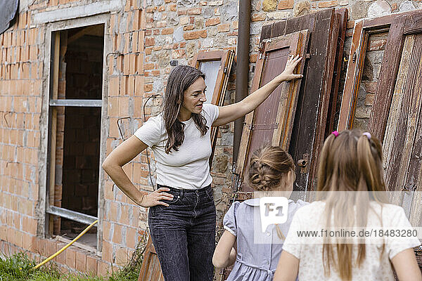 Woman with daughters standing by wooden doors at construction site