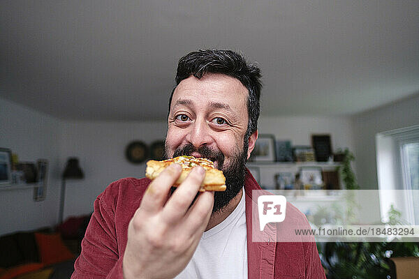 Happy man eating pizza at home