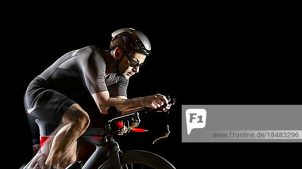 Cyclist sitting on turbo trainer against black background