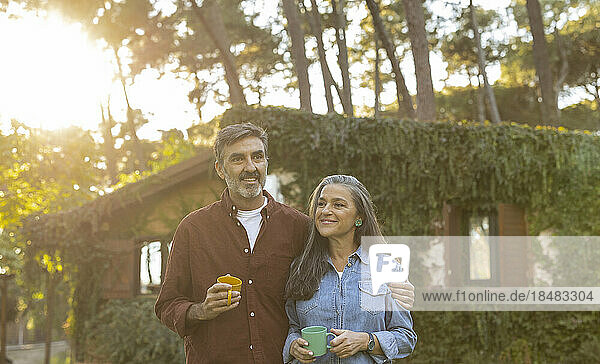 Happy affectionate mature couple standing outside building at sunset