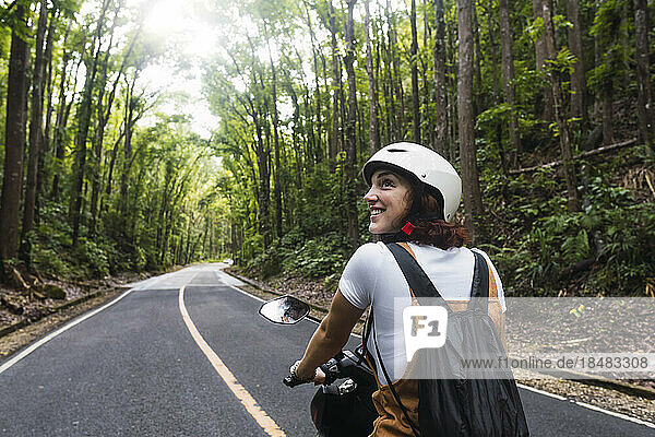 Happy woman wearing helmet riding motorcycle on road