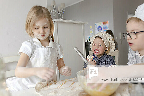 Kinder bereiten in der Küche Teig mit Mehl zu