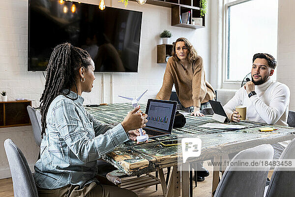 Businesswoman showing wind turbine to colleagues in office