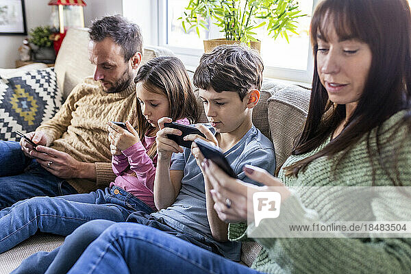 Familie benutzt Mobiltelefon zu Hause auf dem Sofa