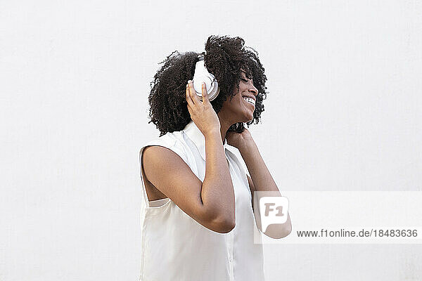 Eine glückliche Frau mit Kopfhörern hört gerne Musik vor weißem Hintergrund