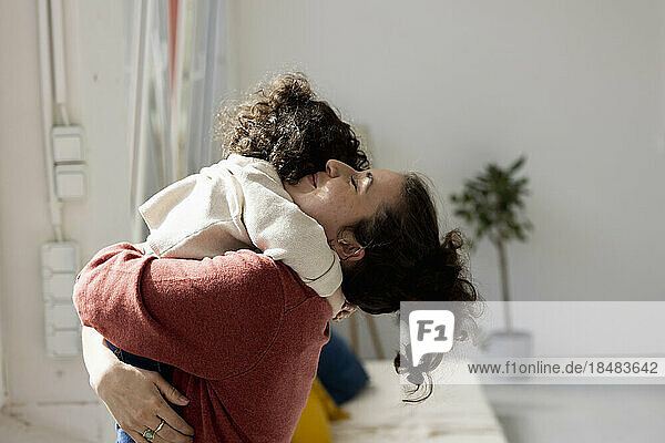 Mutter hält und kuschelt kleine Tochter zu Hause
