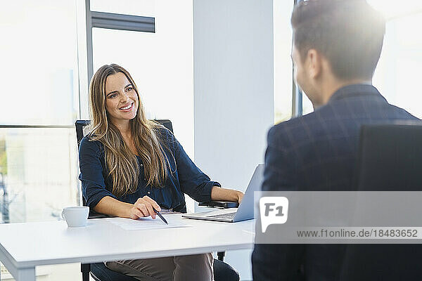Smiling recruiter discussing with candidate at office