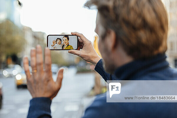 Man waving at family on video call through mobile phone